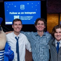 3 boys and a girl pose with Louie the Laker